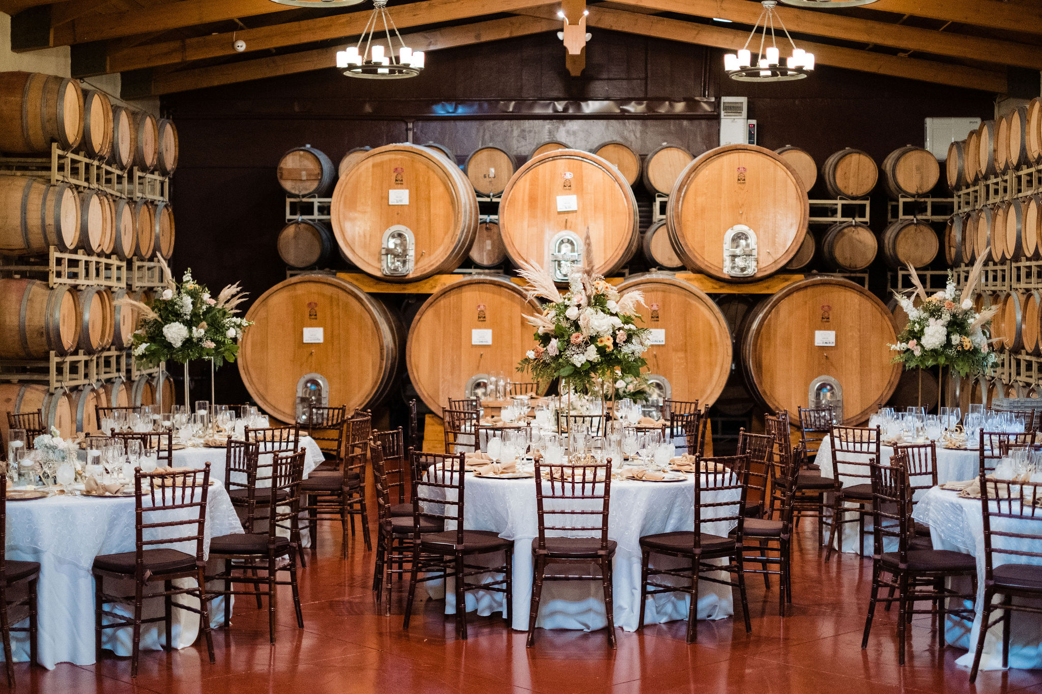 barrel room with wedding reception setup, tables, chairs, floral