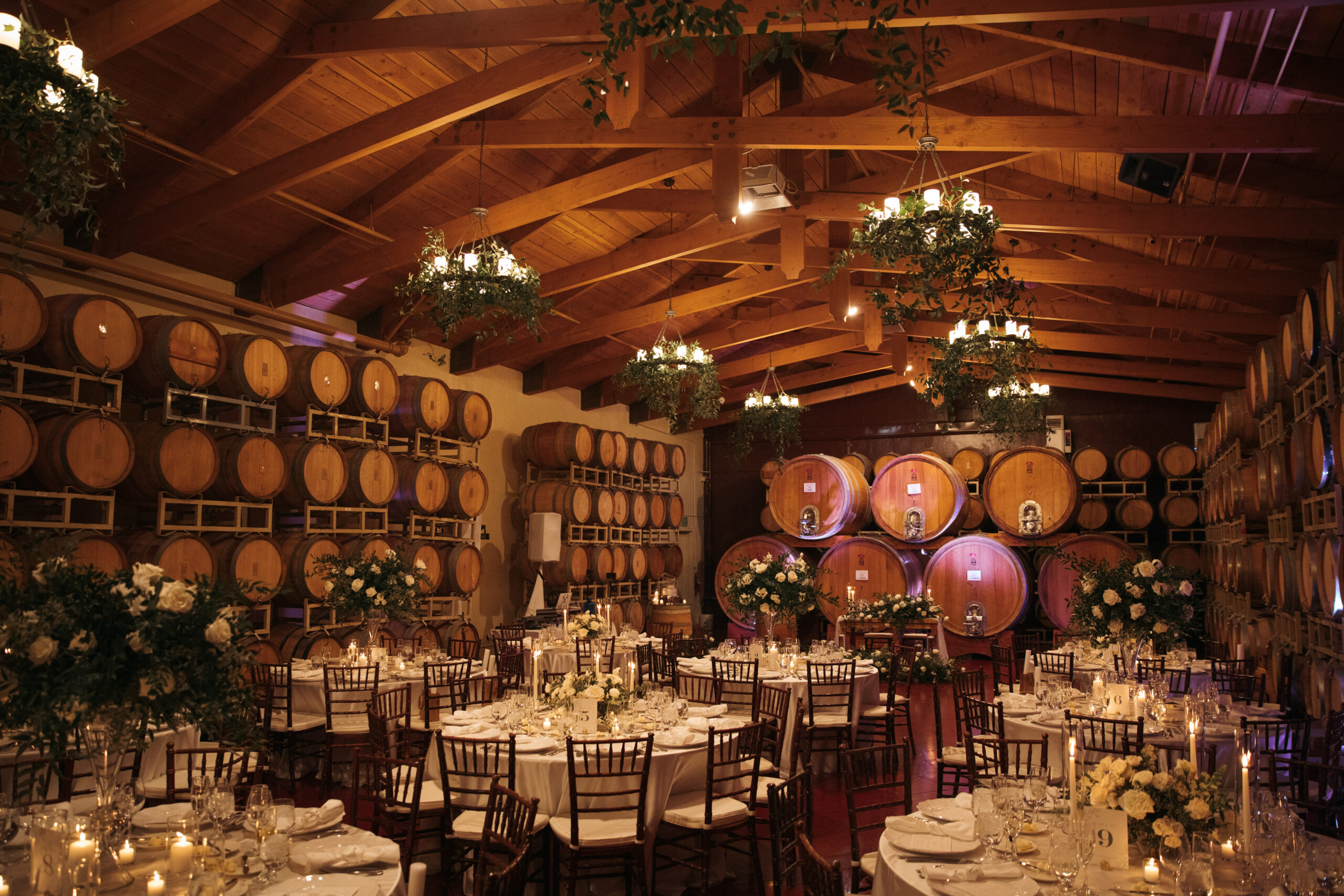 barrel room with wedding reception setup, floral, chairs