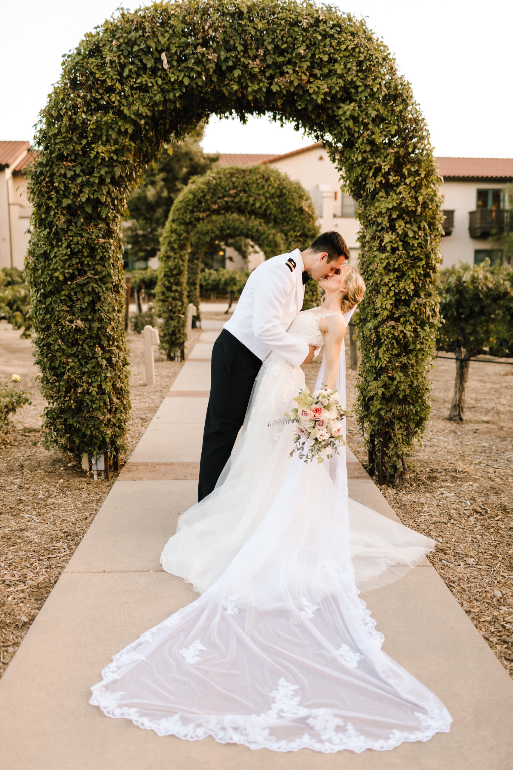 wedding couple kissing at the tunnel of love/ archway