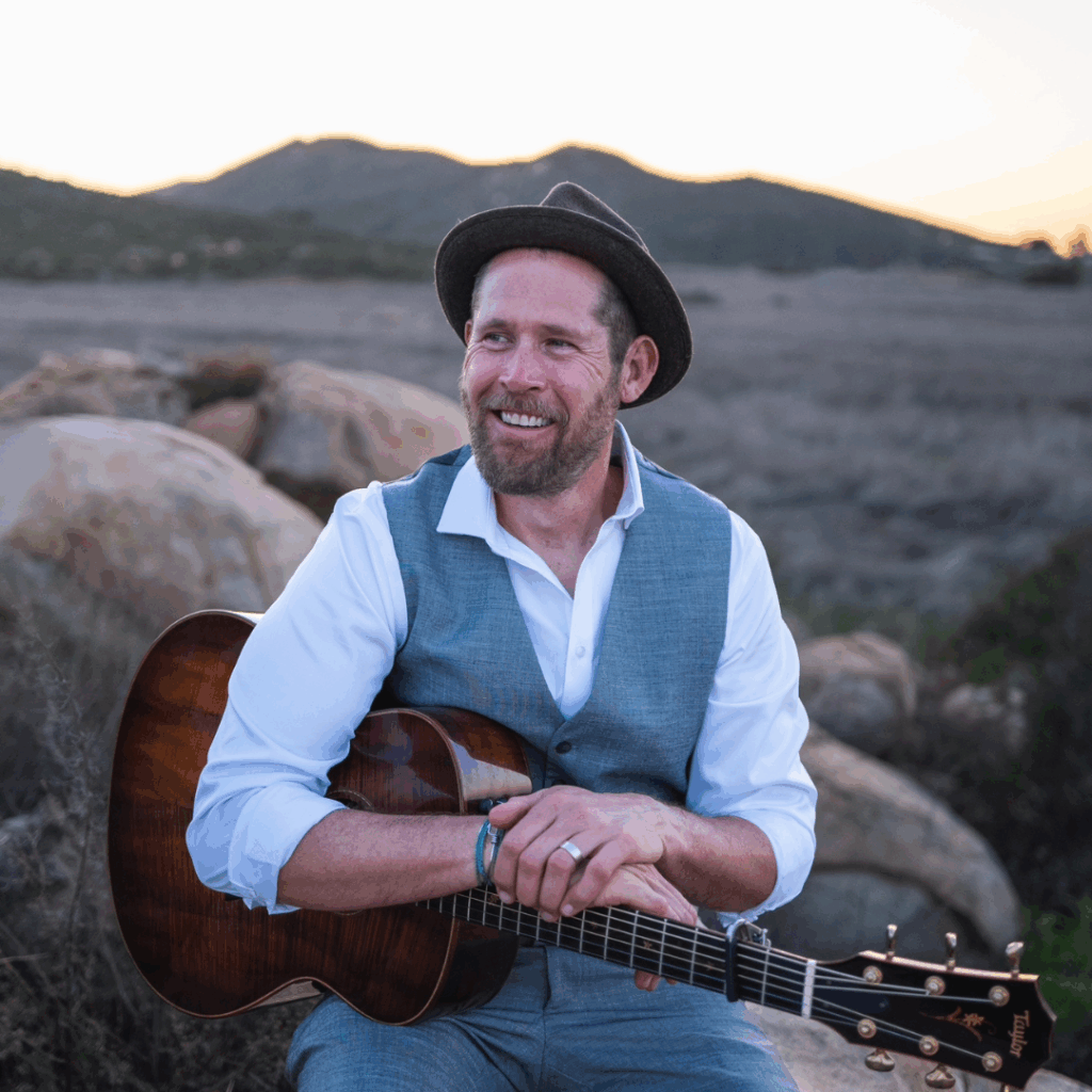 Jeff Brinkman posing with their guitar for a photo
