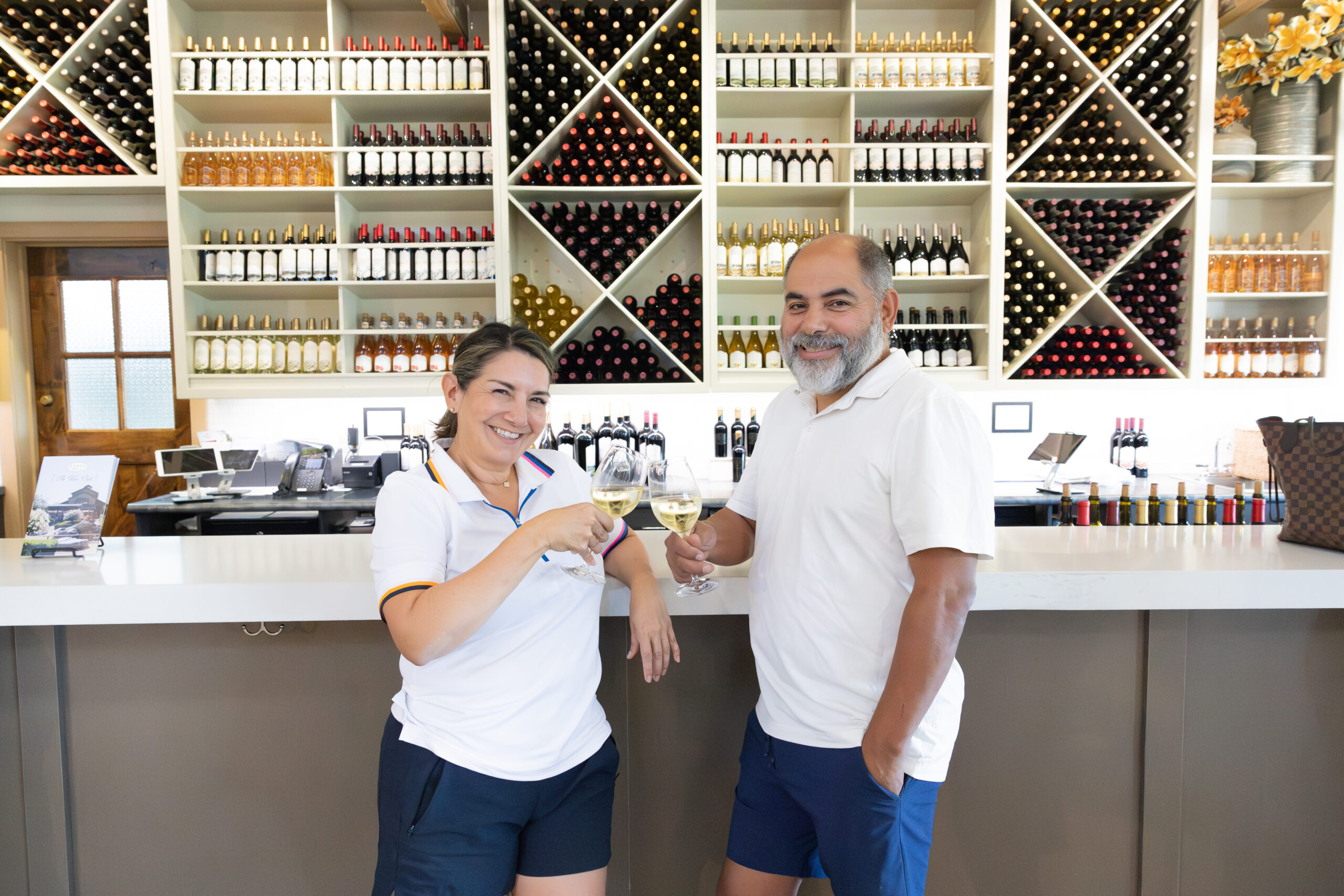 a couple cheering their glasses in the wine tasting room smiling for the camera