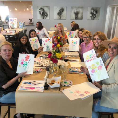 Group of women showing their canvas with flower paintings