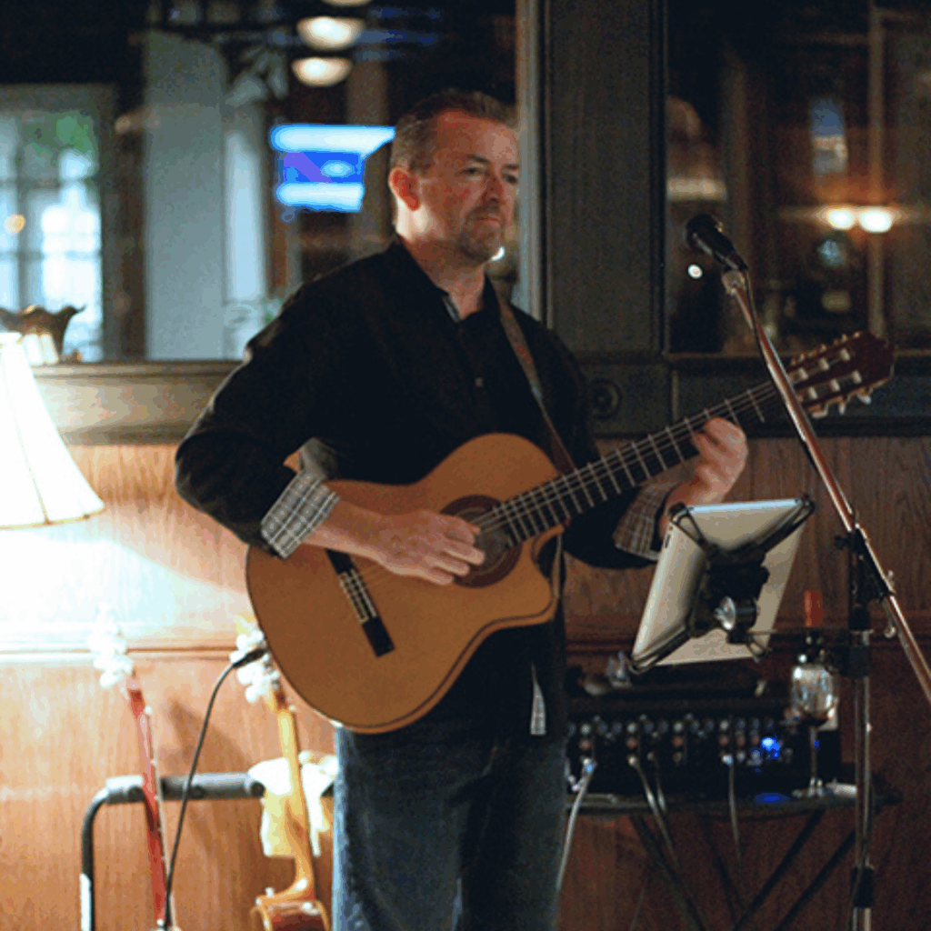 Ted Kassiotis holding a guitar standing